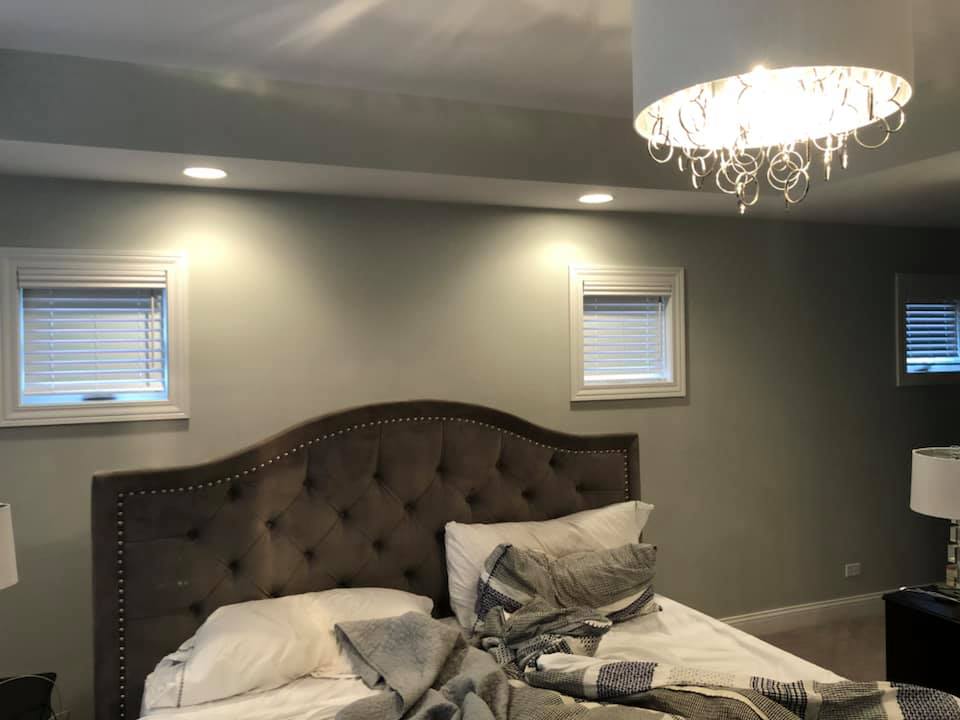 A bedroom with a bed and a chandelier hanging from the ceiling.