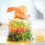 Stack of layered salad with shrimp on top, on a plate.