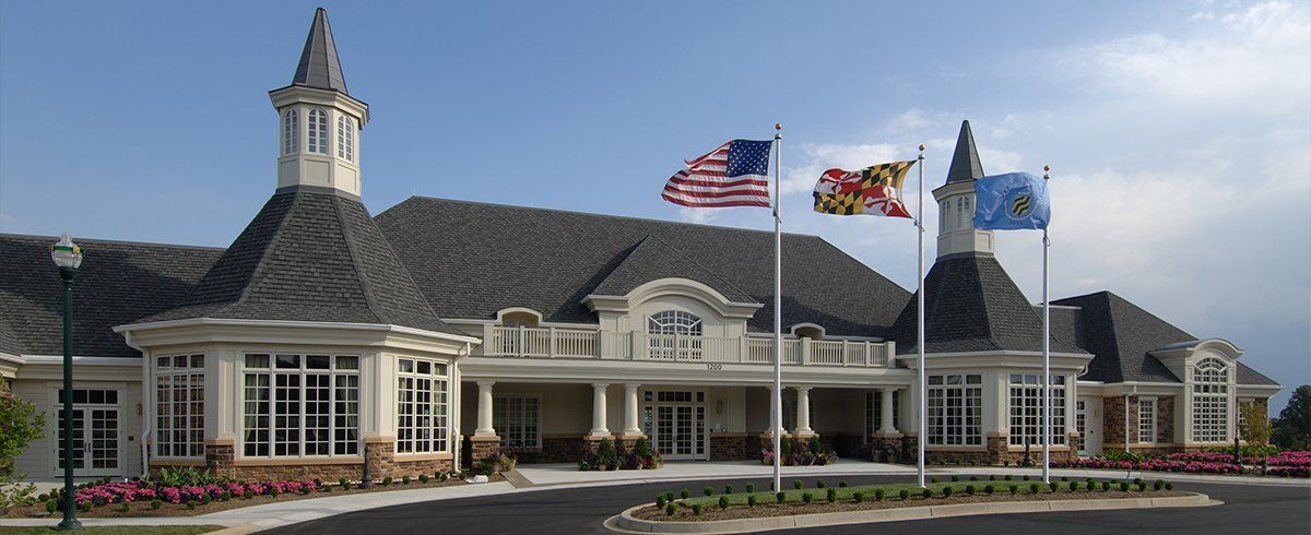 Building with flags; US, Maryland and Delaware flags fly. Formal architecture with a blue sky backdrop.