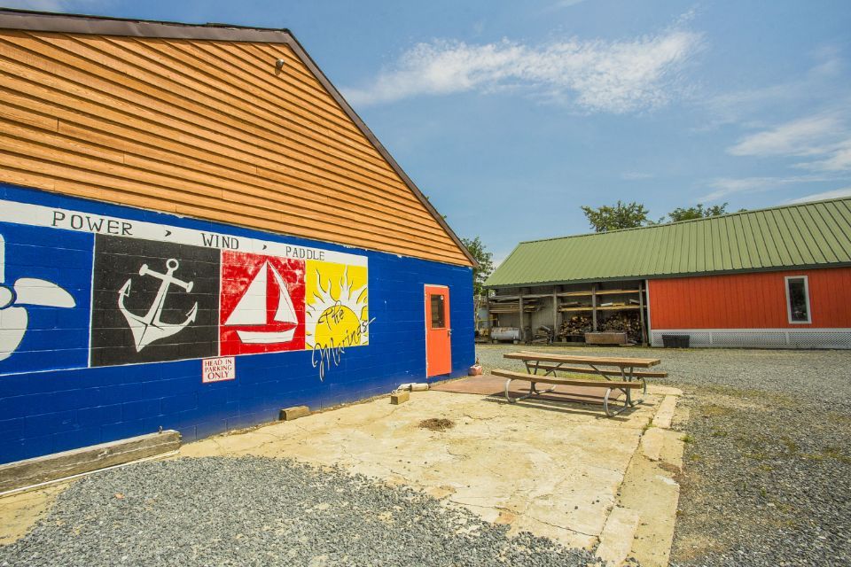 Blue building with nautical symbols on a wall, picnic table outside. Another building visible in the background.