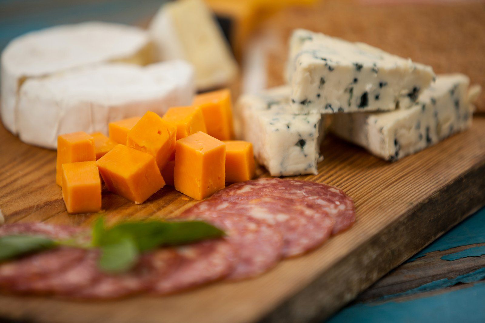 A wooden cutting board topped with a variety of cheeses and meats.