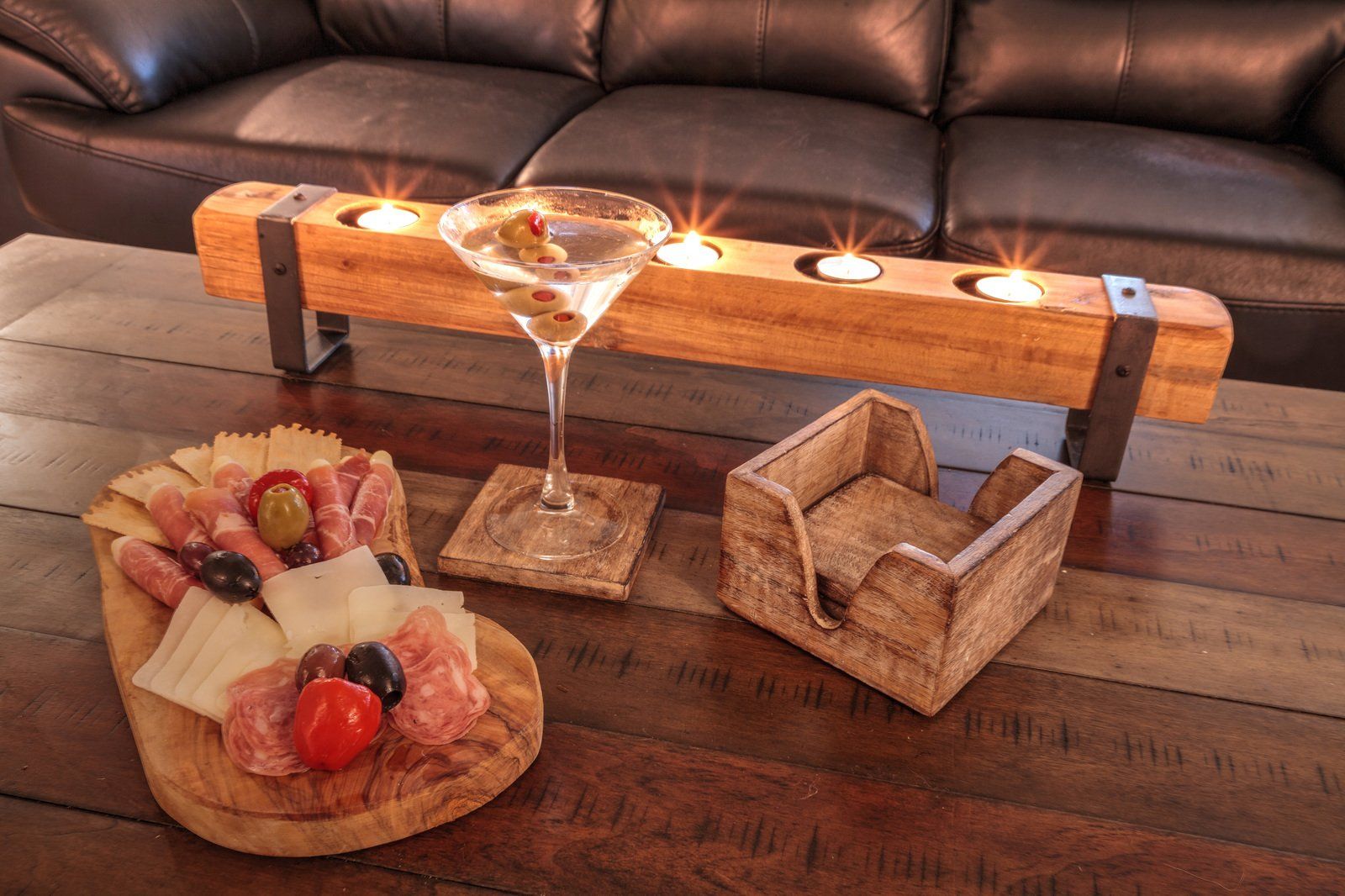 A martini glass is sitting on a wooden table next to a tray of food.