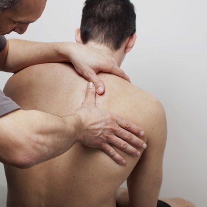 Shoulder injury assessment A therapist examining a man's right shoulder blade