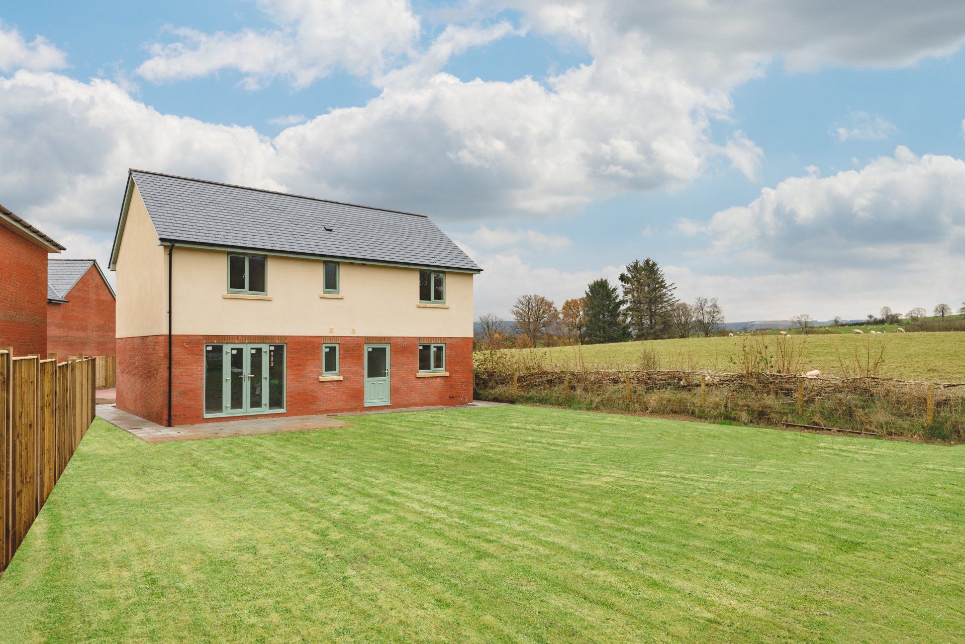 View of Tretower (plot 1) from the garden, nestled next to a field of grazing sheep.