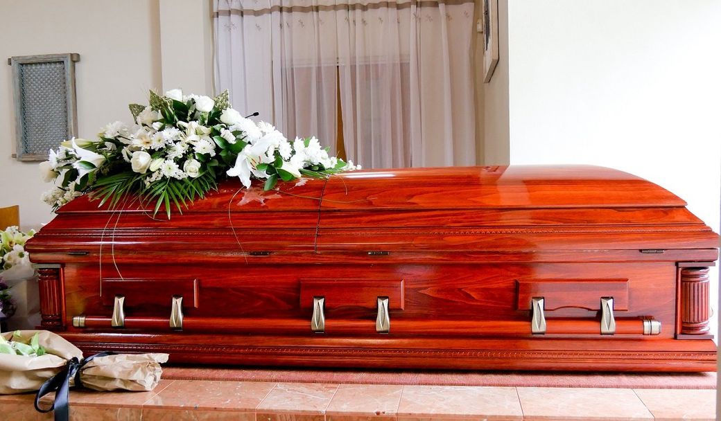 cofano funebre in legno con cuscino di fiori