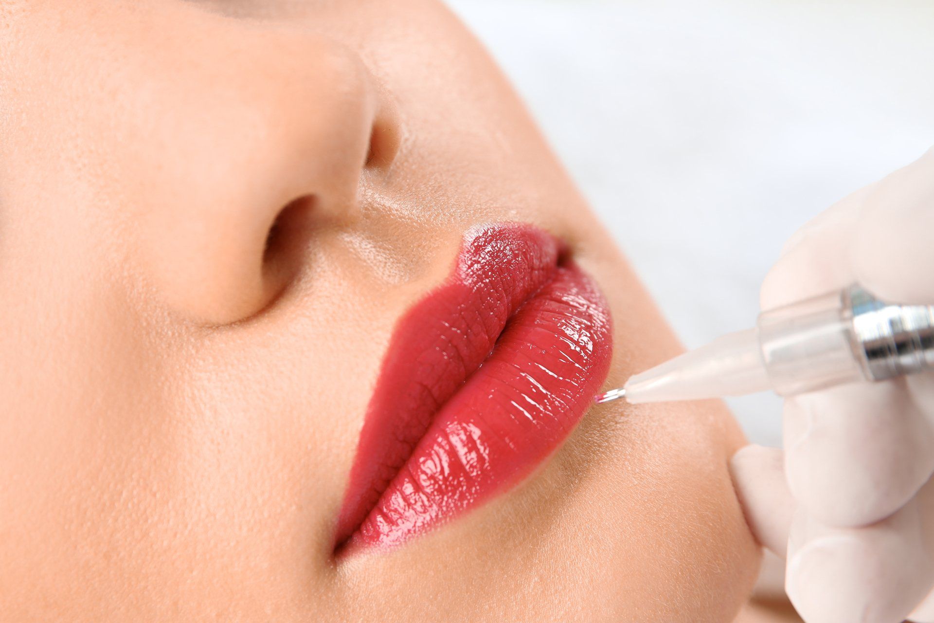 Eine Frau lässt sich ein permanentes Lippentattoo auf die Lippen stechen.
