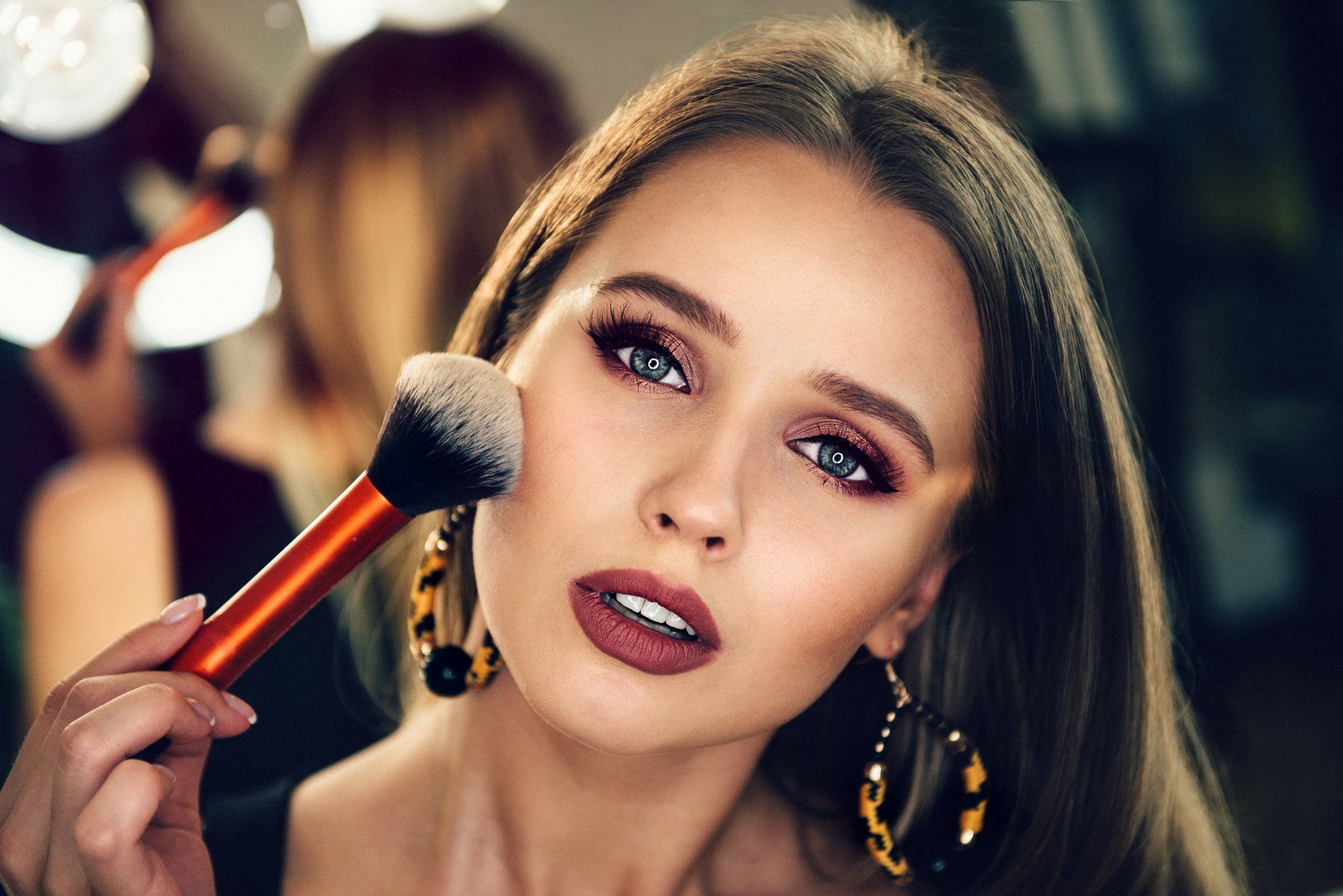 Eine Frau trägt mit einem Pinsel Make-up auf ihr Gesicht auf.