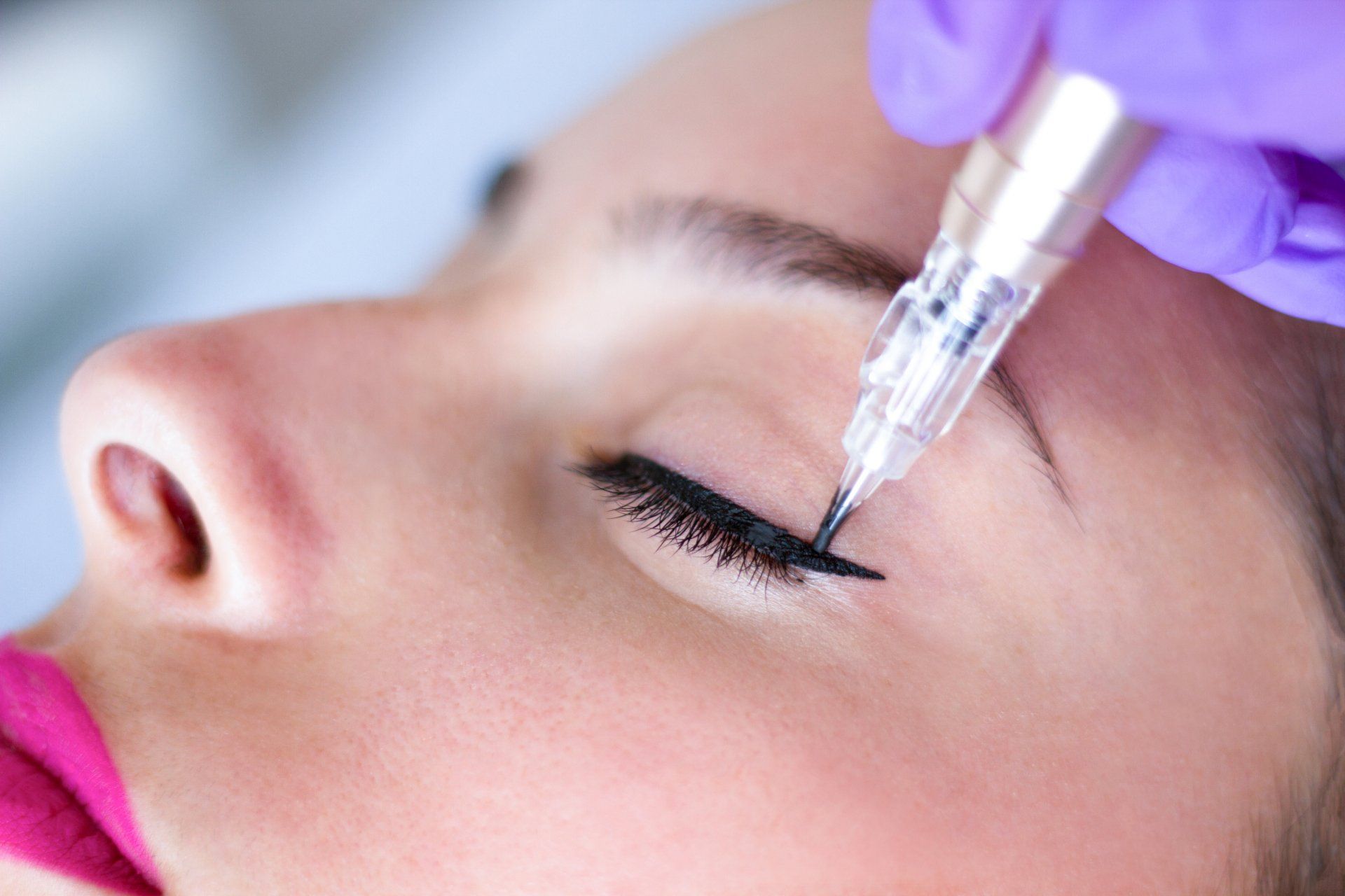 Eine Frau lässt sich ein permanentes Eyeliner-Tattoo aufs Auge stechen.