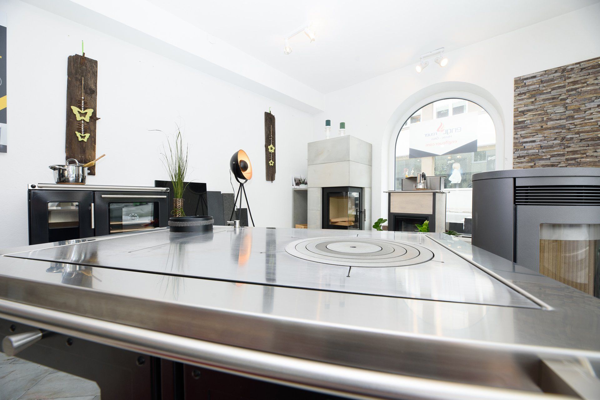 Moderne Küche mit Edelstahlinsel, schwarzen Schränken und Steinkamin in einem hellen, offenen Raum
