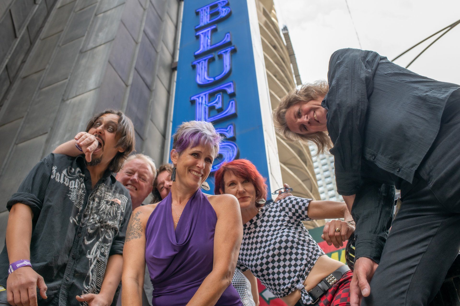 A group of people are posing for a picture in front of a blue sign that says blues.