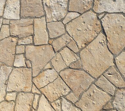 Patio z jasnego kamienia o nieregularnych kształtach i ciemną fugą.