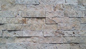 Mur kamienny z prostokątnych bloków w odcieniach beżu i szarości.