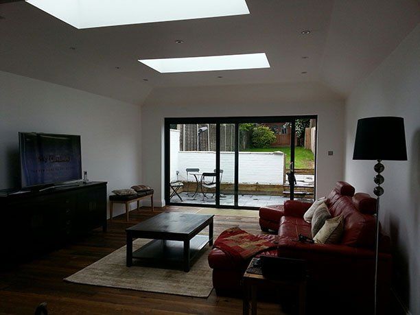 Tv room renovation that have new, modern floor to ceilings patio door windows.