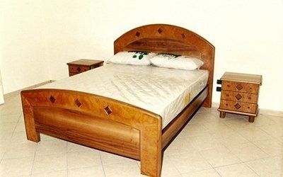 Struttura del letto in legno con materasso, cuscini e due comodini coordinati in una stanza.
