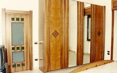 Armadio in legno con ante a specchio accanto a un'anta con pannelli in vetro.