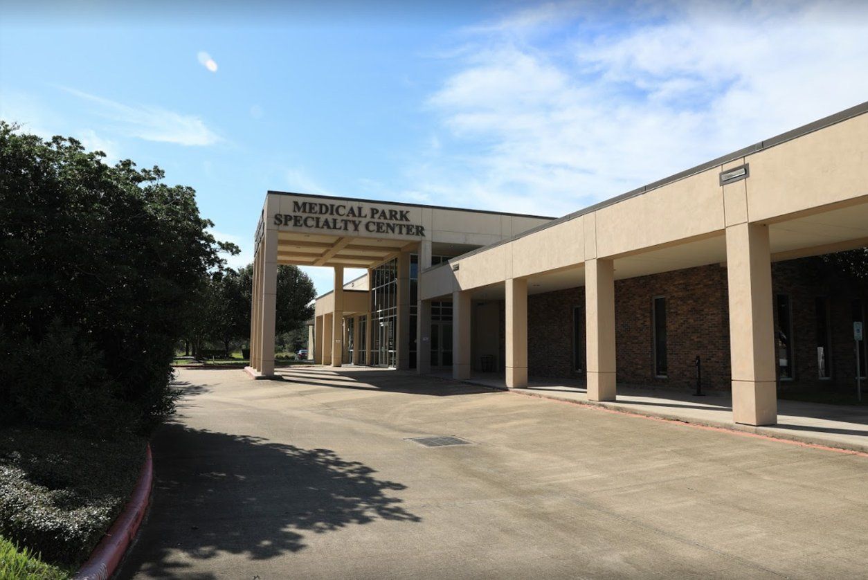The beige Medical Park Specialty Center building with a covered entryway under a clear blue sky.