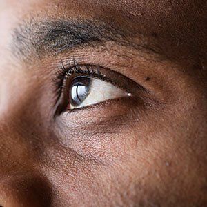 Close-up view of a person’s eye looking upward, focusing on the iris and eyelashes.