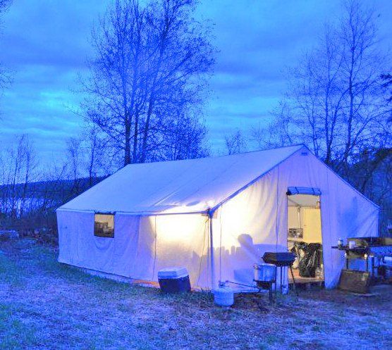 A white tent is lit up at night in a field.