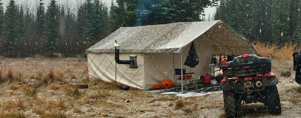 A tent is sitting in the middle of a field next to a atv.