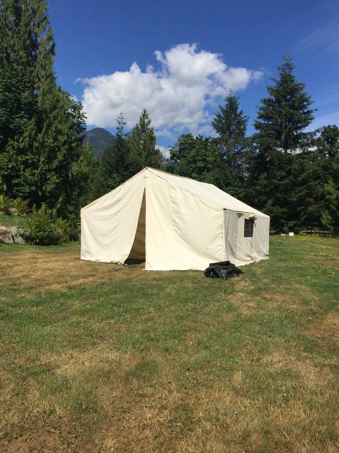 A large white tent is sitting in the middle of a grassy field.