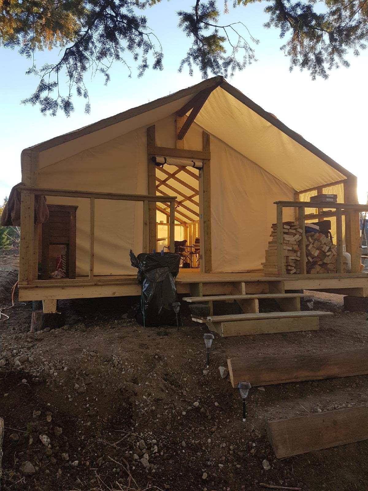 A small wooden house with a tent on top of it