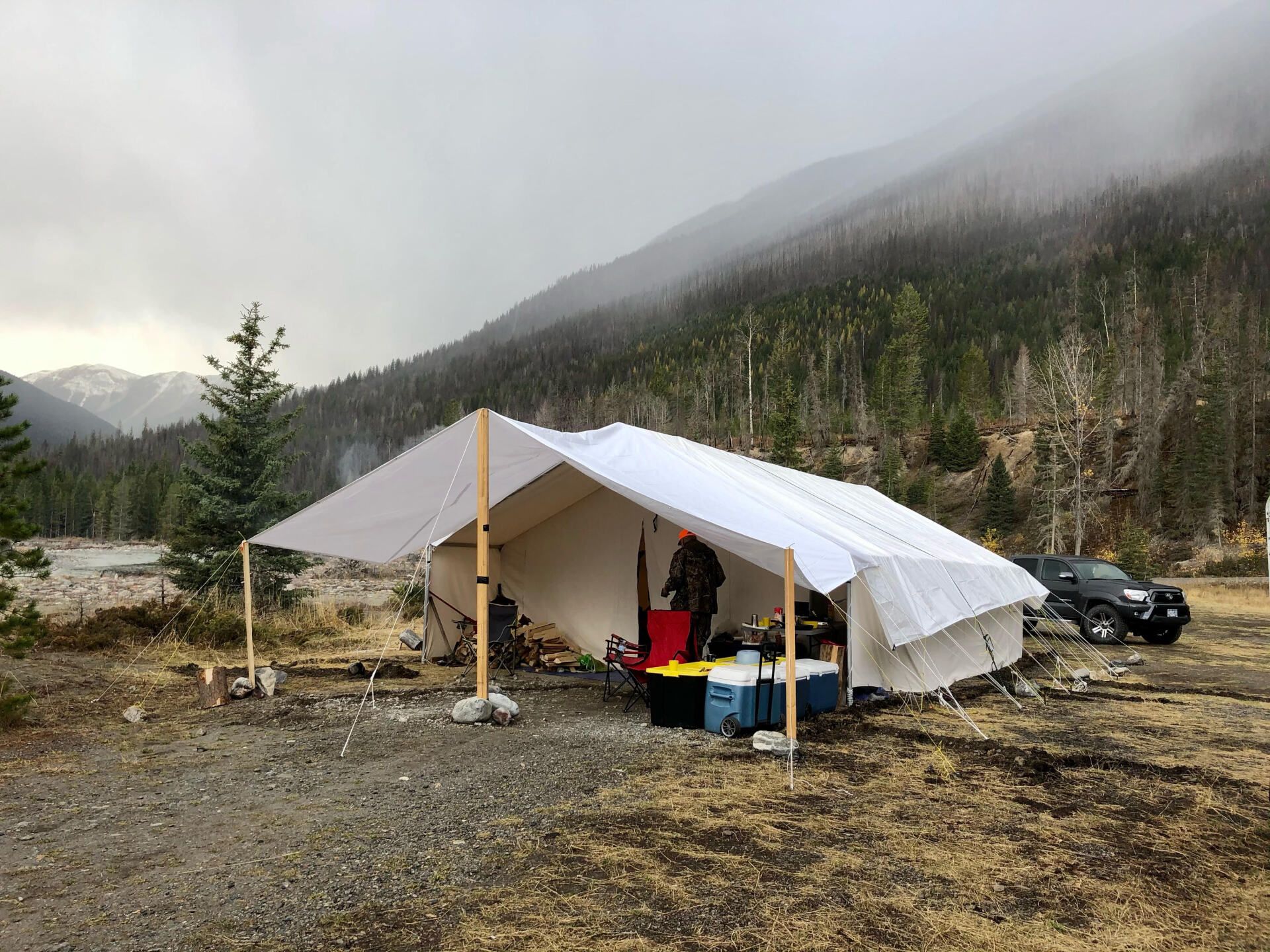 A tent is sitting in the middle of a field in front of a mountain.