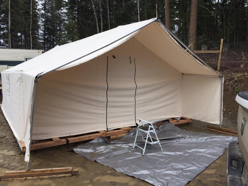 A white tent is sitting on a tarp in the dirt
