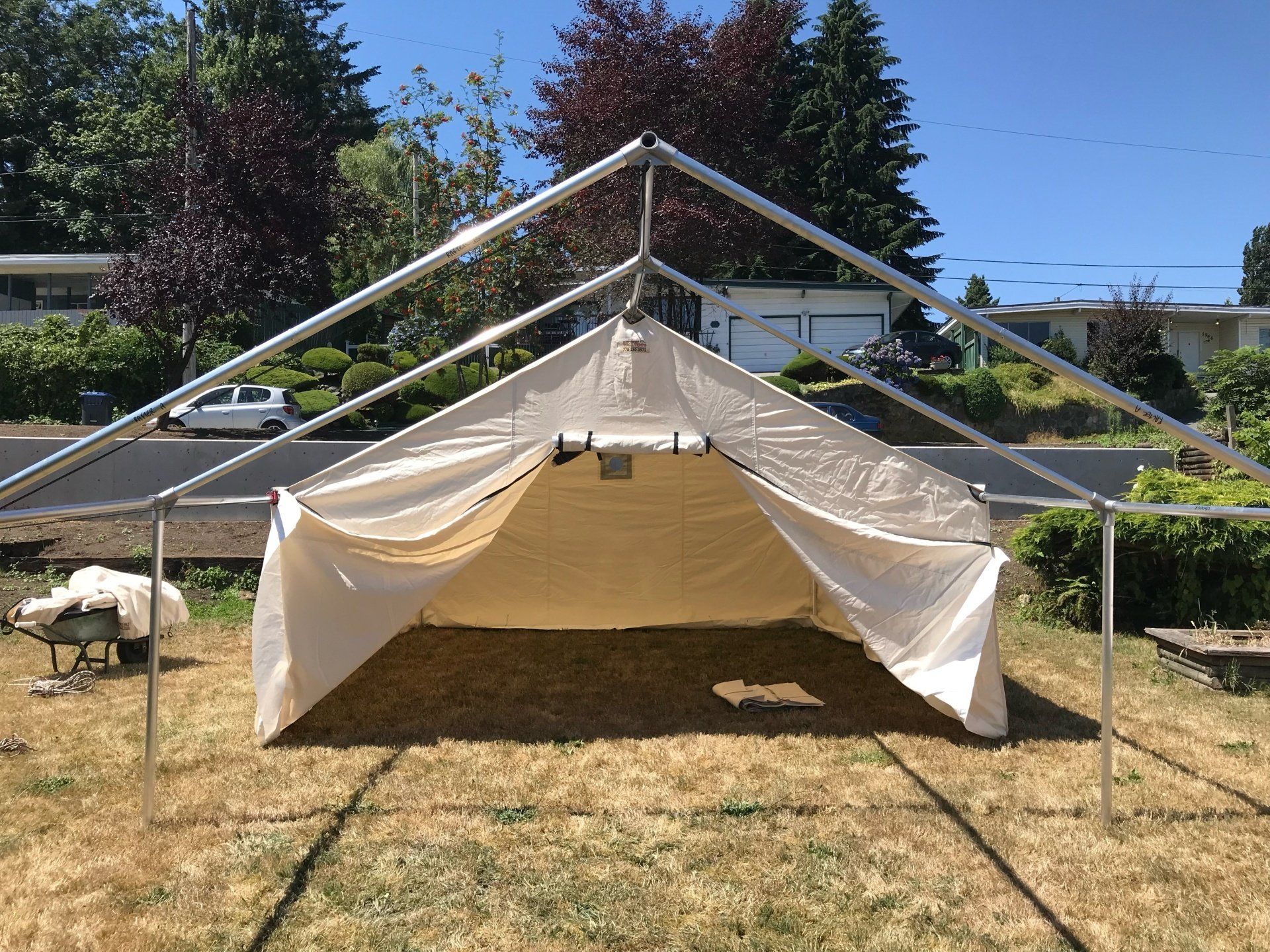 A white tent is sitting in the middle of a grassy field.