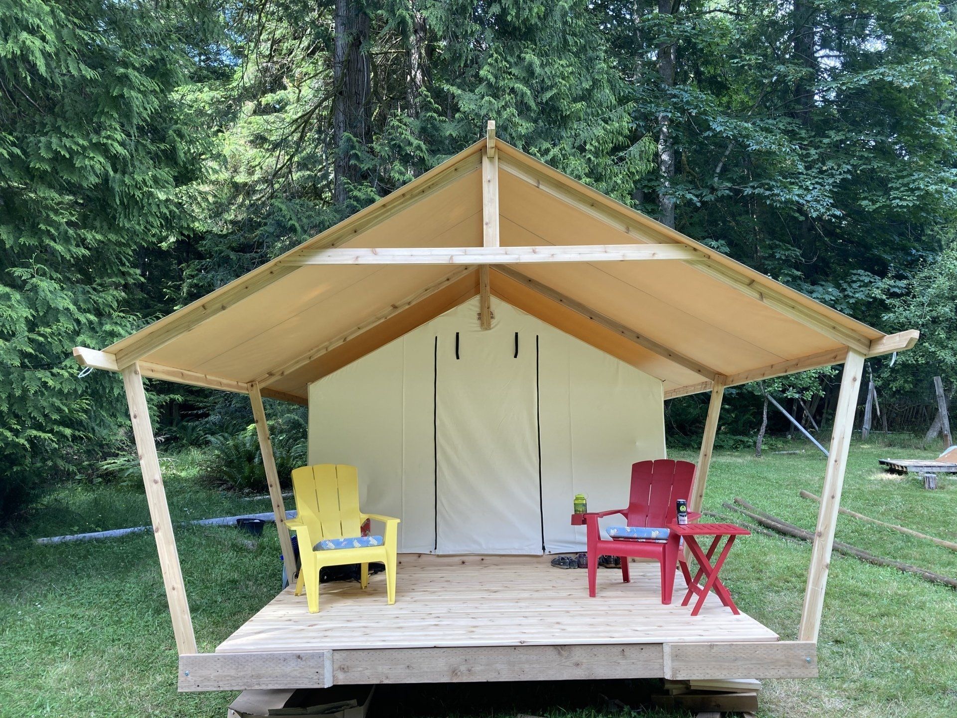 A tent with two yellow chairs and two red chairs in front of it