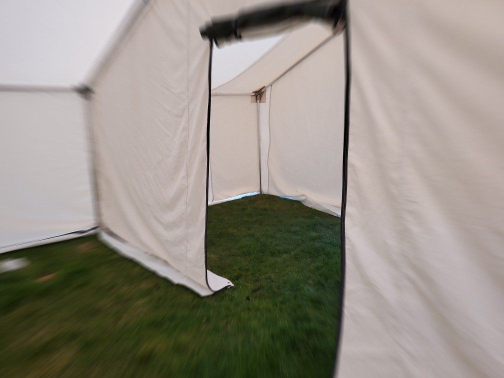 A white tent is sitting on top of a lush green field.