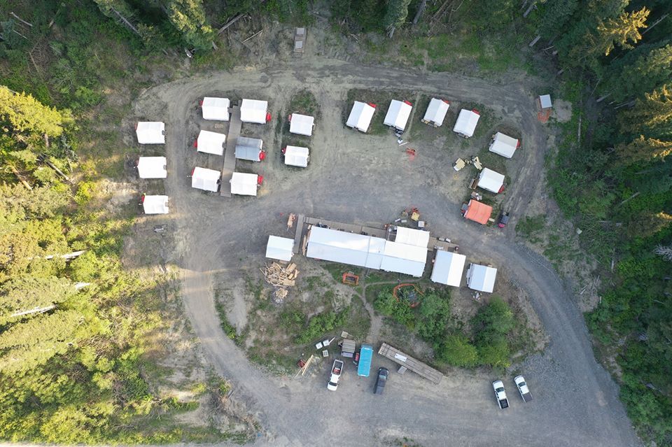 An aerial view of a campground with tents and cars parked in a circle.