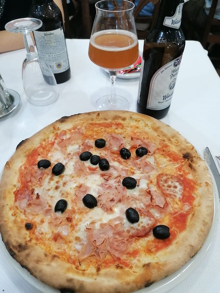 Pizza con mozzarella, pomodoro, prosciutto cotto e olive nere