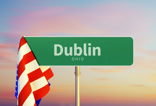 A street sign for Dublin Ohio with an American flag behind it
