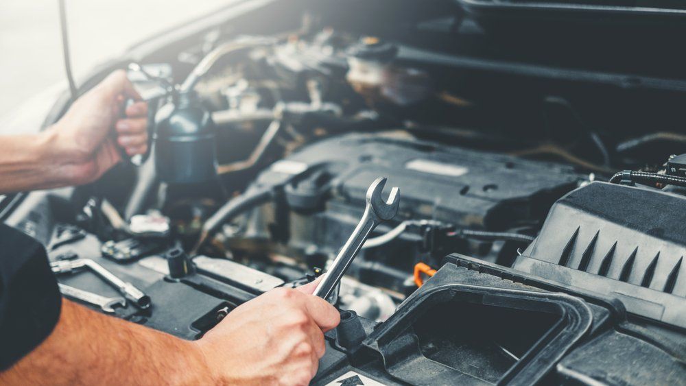 Un homme travaille sur le moteur d'une voiture avec une clé.