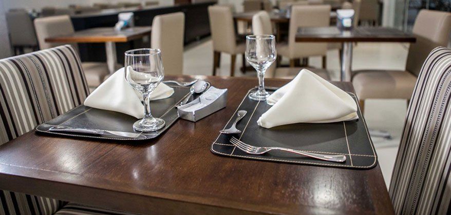 Uma mesa de restaurante com pratos, guardanapos, copos e talheres.