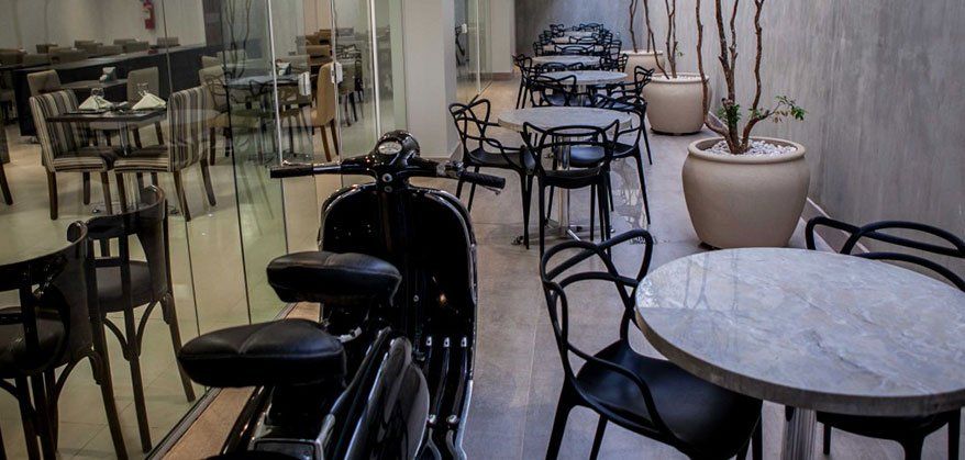Uma motocicleta está estacionada no meio de um restaurante com mesas e cadeiras.