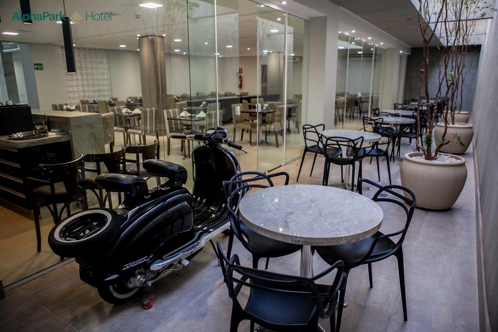 Uma motocicleta está estacionada em frente a um restaurante com mesas e cadeiras.