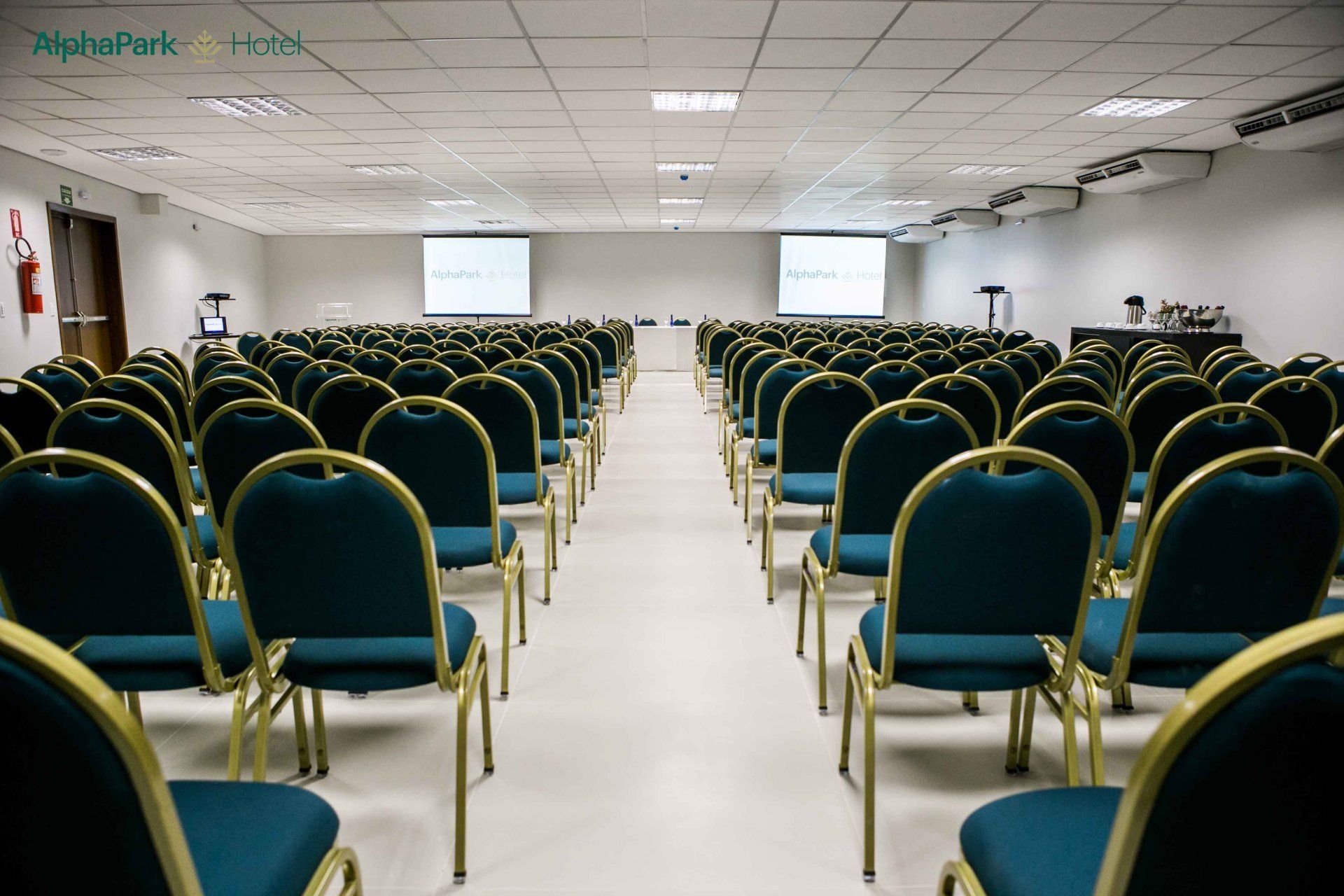 Fileiras de cadeiras em uma sala grande com uma tela de projetor