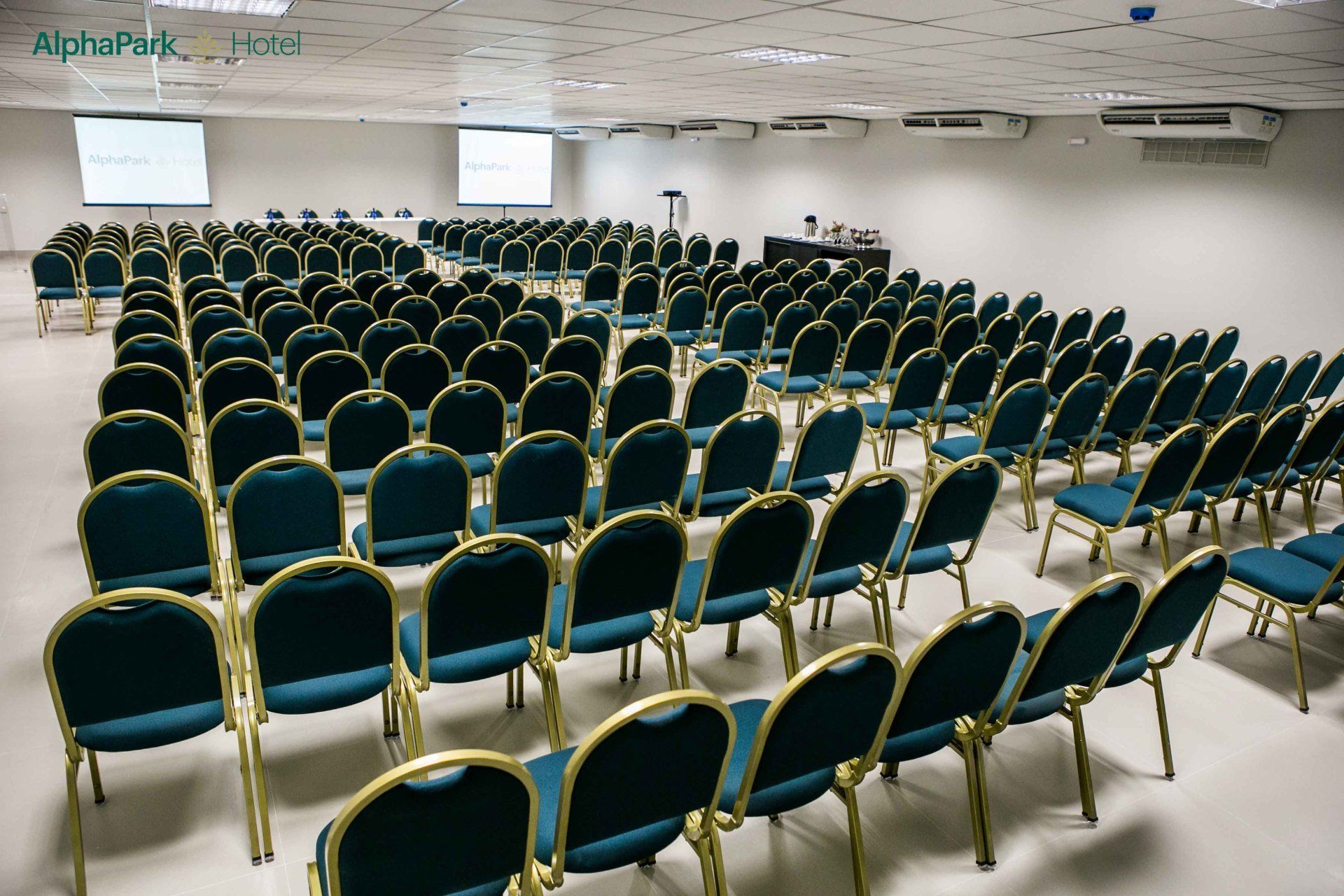 Fileiras de cadeiras azuis em uma sala grande com uma placa que diz aprepark
