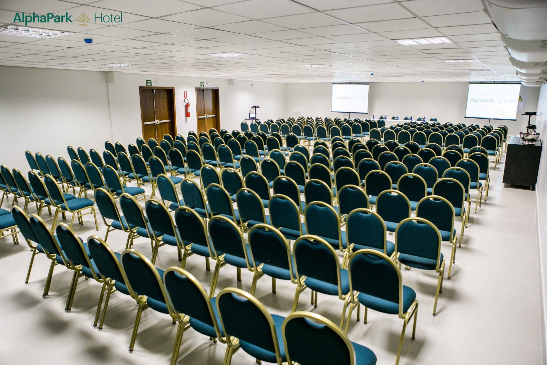 Fileiras de cadeiras azuis estão alinhadas em uma grande sala