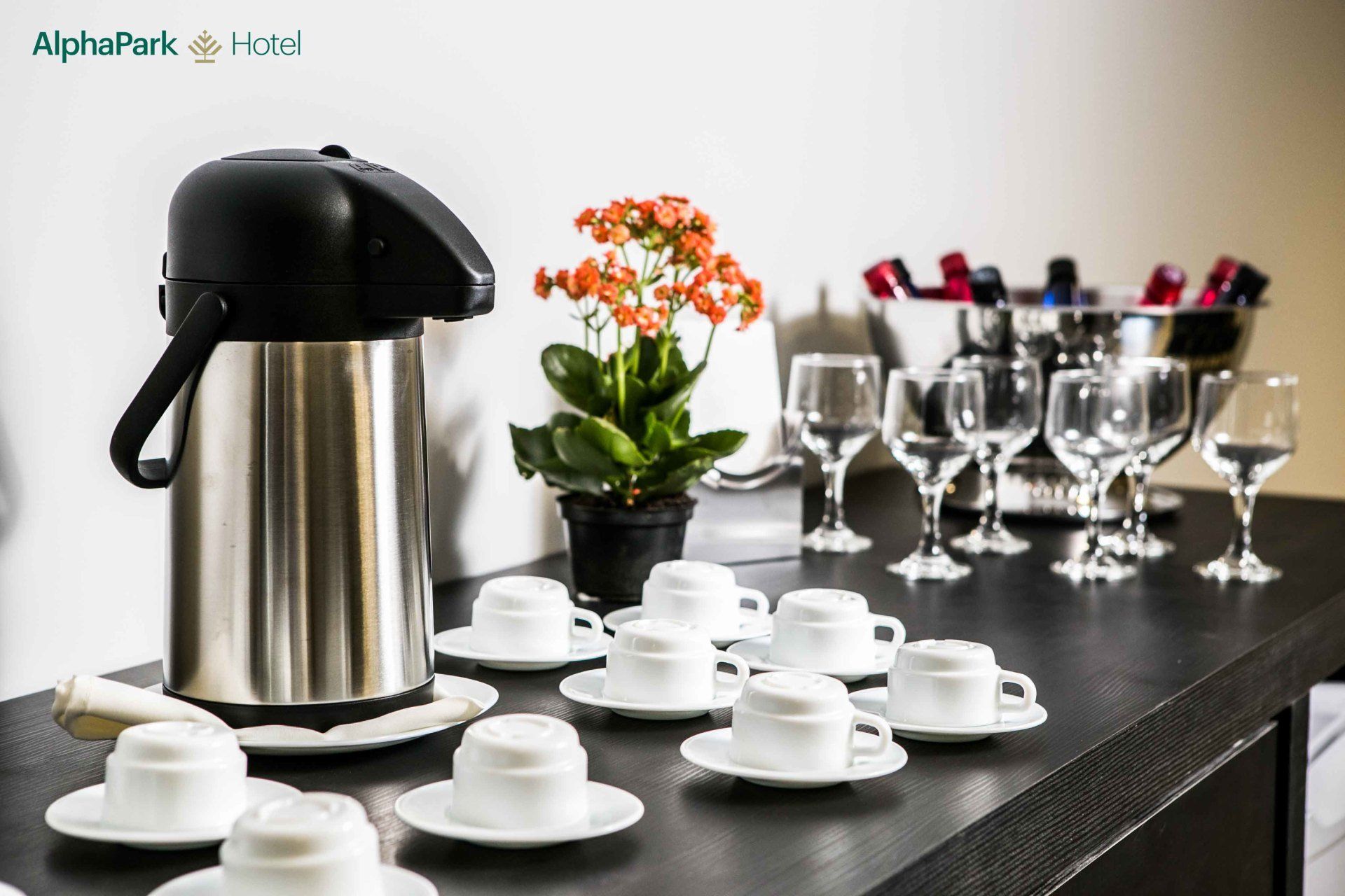 Uma mesa com xícaras de café, taças de vinho e uma planta em vaso.