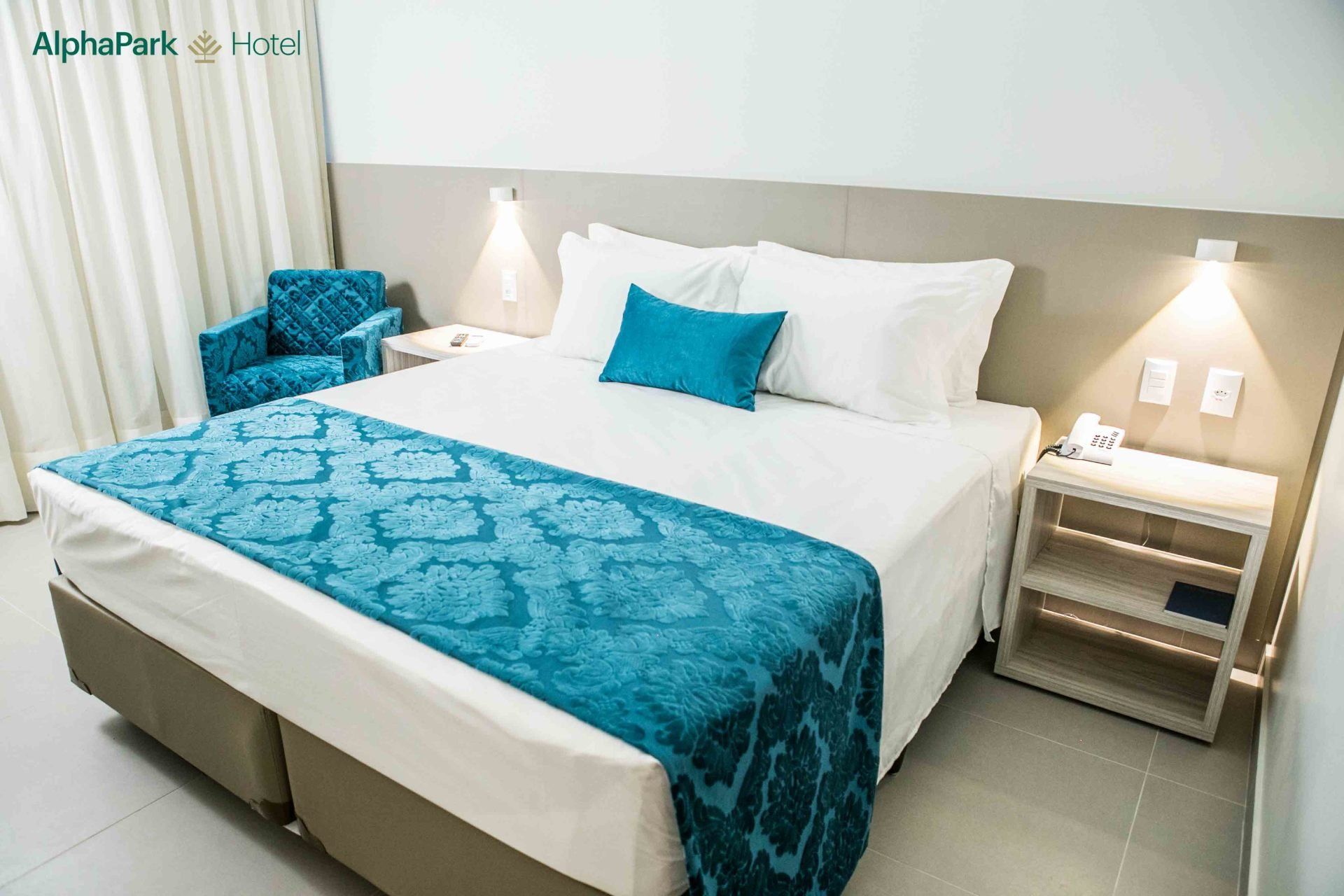 Um quarto de hotel com uma cama king size e uma cadeira.