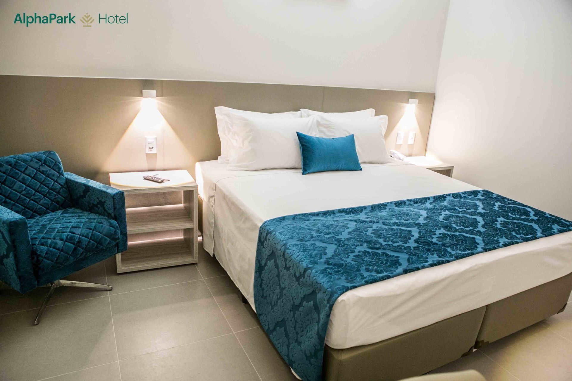 Um quarto de hotel com uma cama, cadeira e mesa de cabeceira.