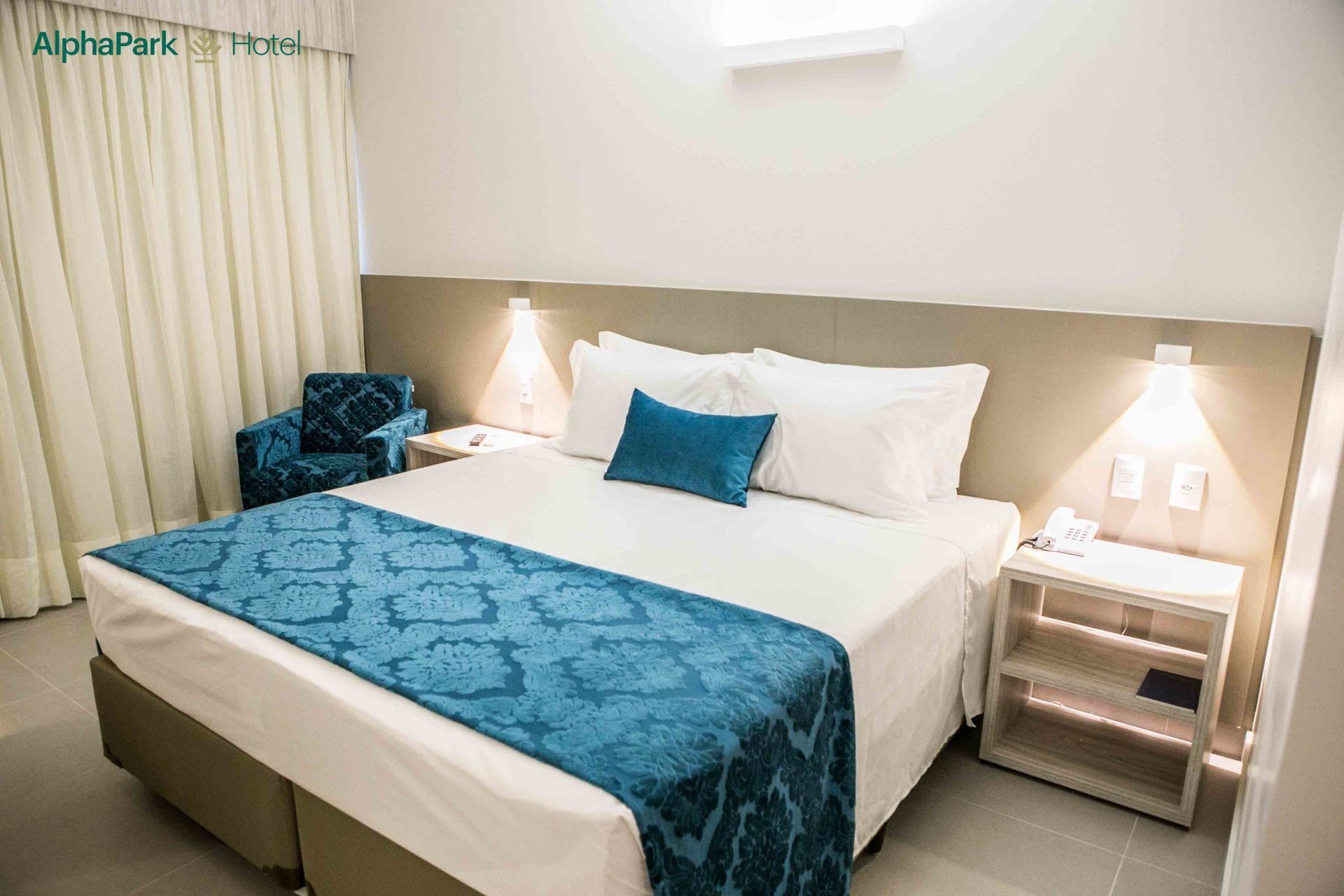 Um quarto de hotel com uma cama king size e uma cadeira.