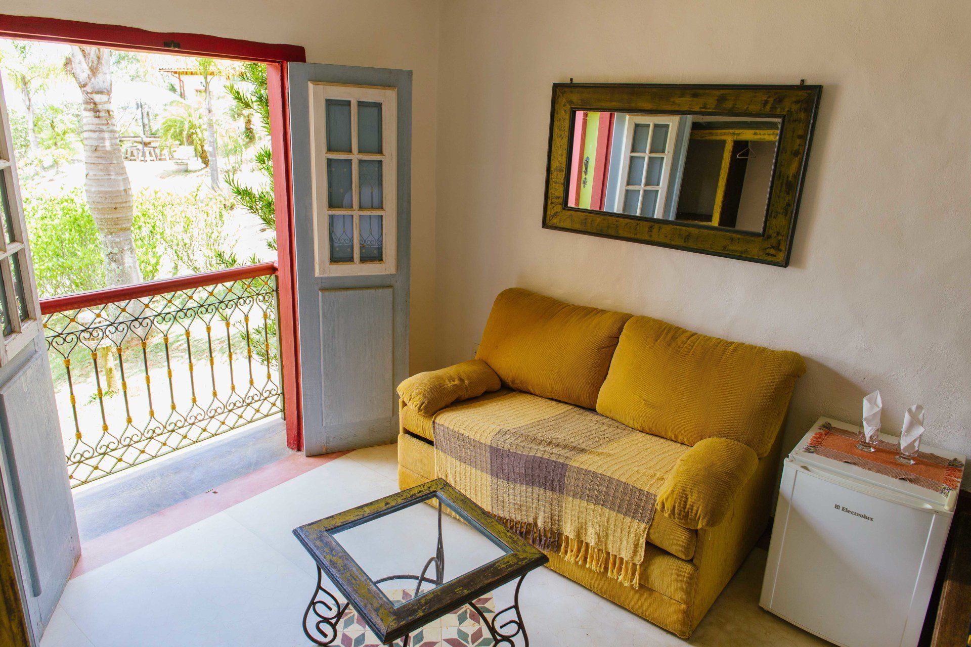 Uma sala de estar com um sofá amarelo e uma mesa de vidro