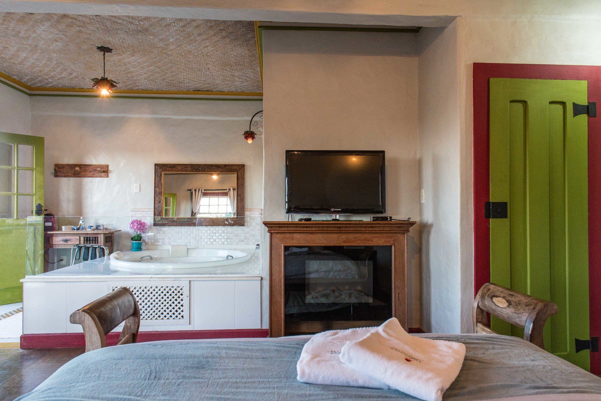 Um quarto com cama, televisão, lareira e banheira.
