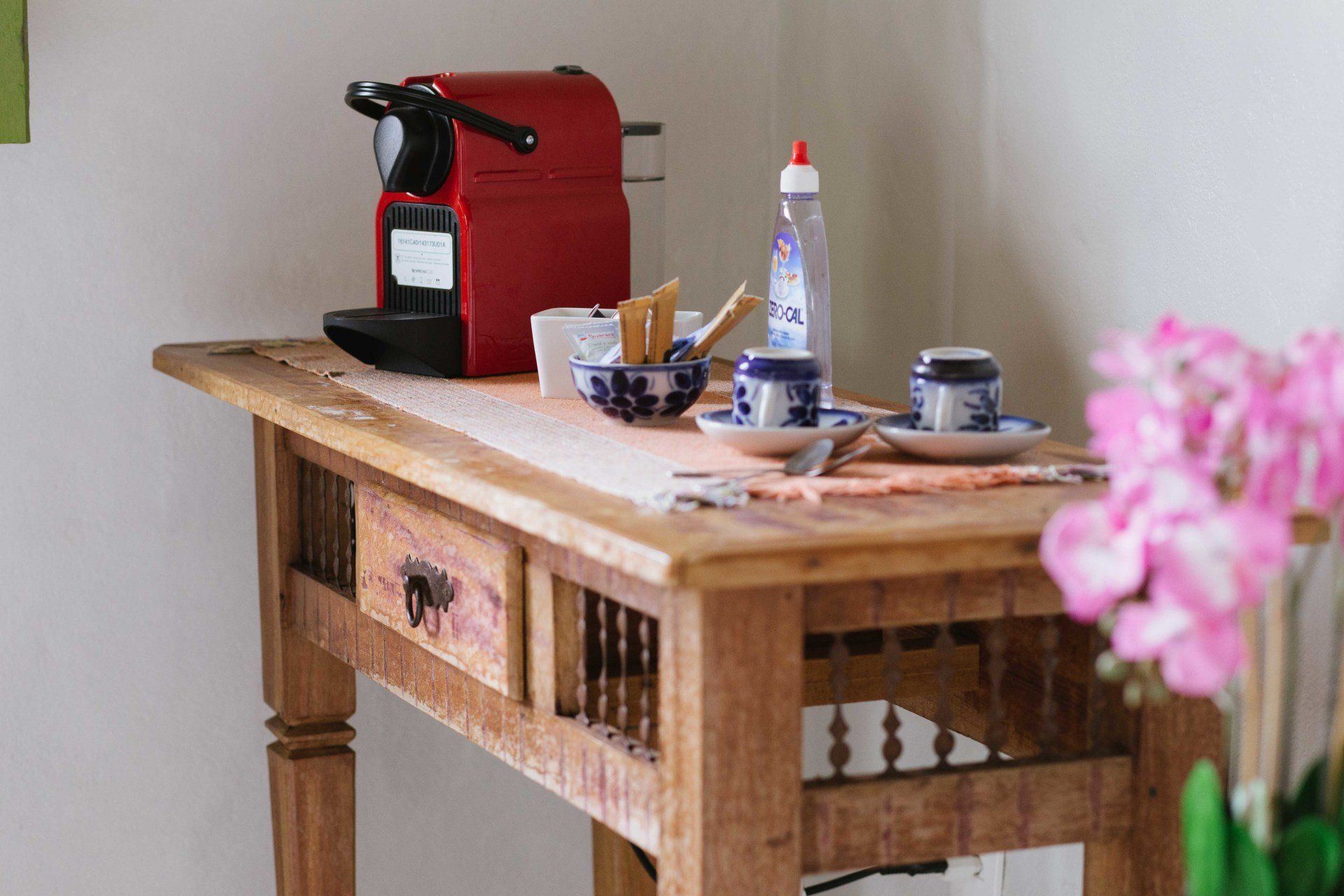 Uma mesa de madeira com uma cafeteira, xícaras e pires.