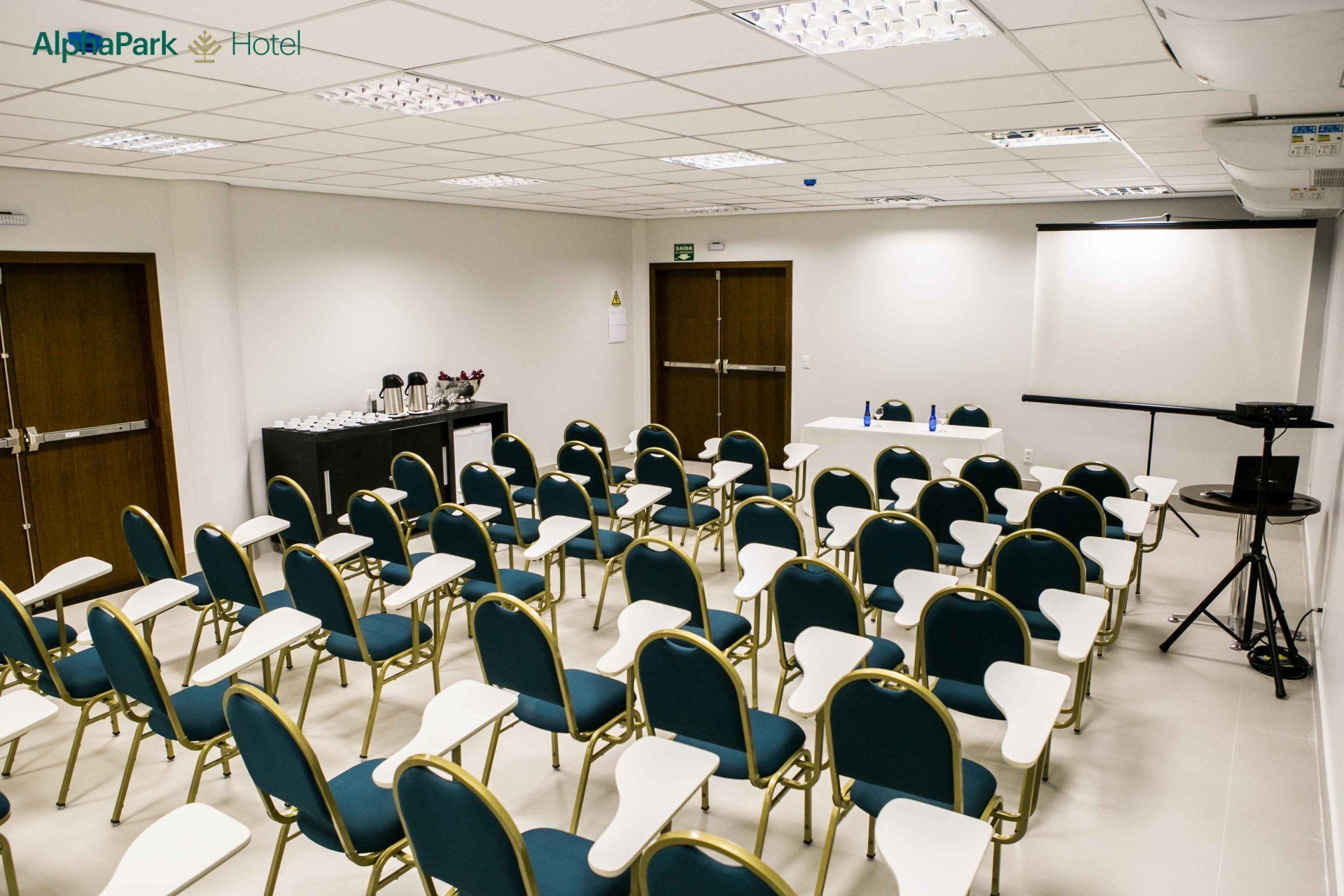 Uma sala de conferências com cadeiras azuis e uma tela de projetor