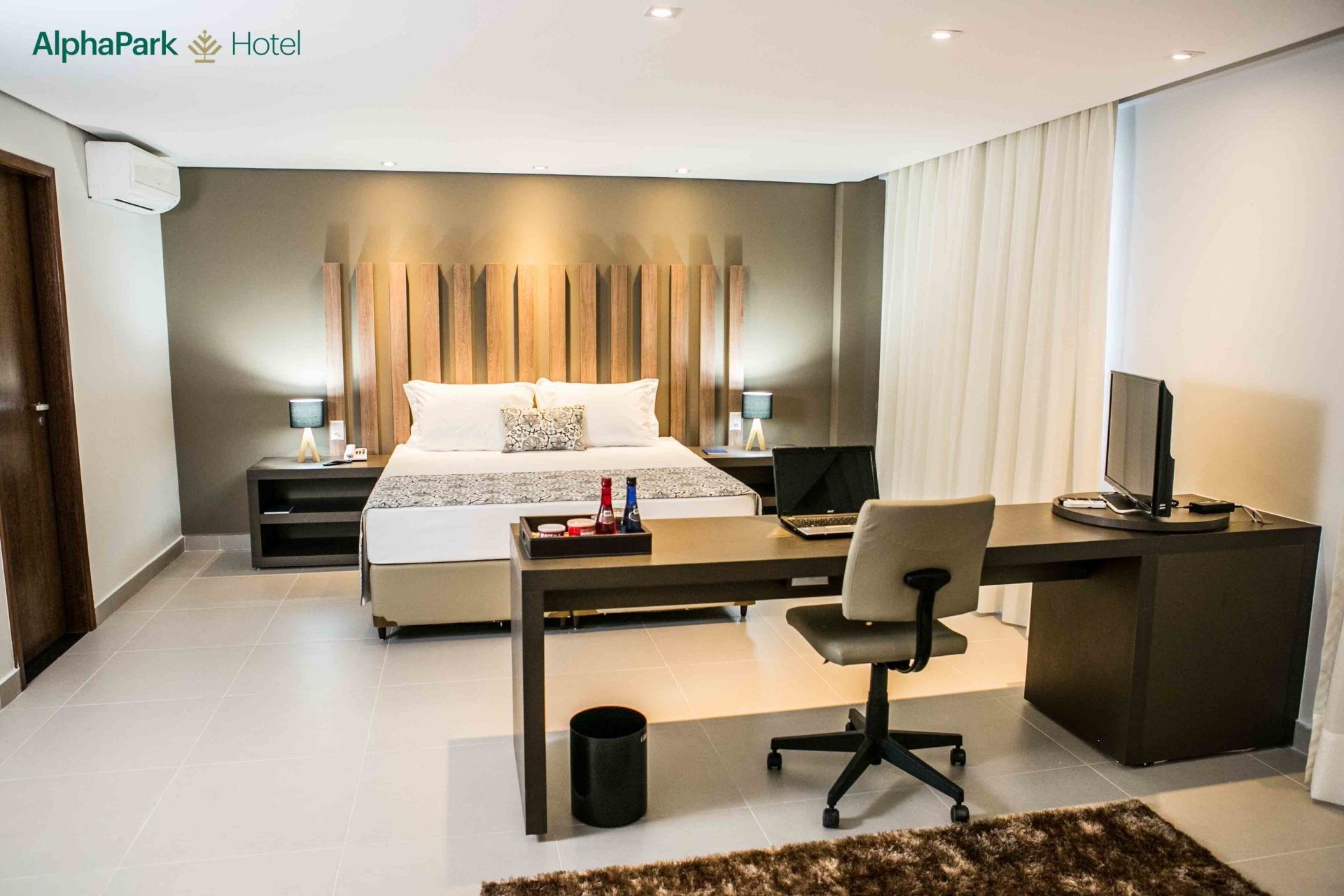 Um quarto de hotel com uma cama, escrivaninha, cadeira e computador.