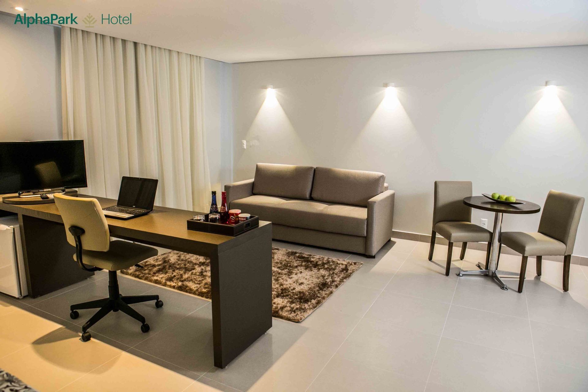 Uma sala de estar com um sofá, escrivaninha, cadeiras e uma mesa.